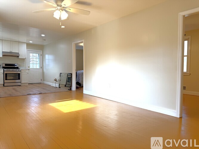 A spacious living room with a ceiling fan and hardwood floors.