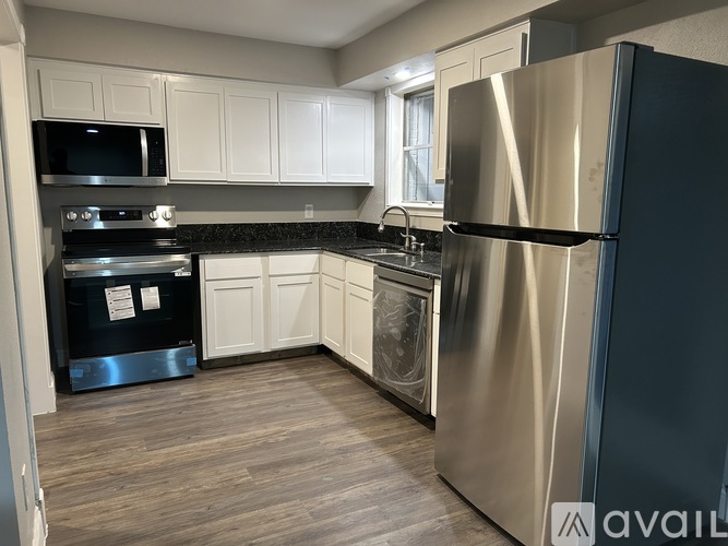 A kitchen with a stainless steel refrigerator and wooden flooring.