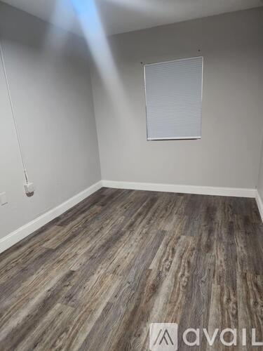 A room with wooden flooring and a window with blinds.