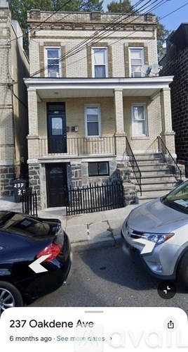 A two-story house with a black door and a balcony on the second floor.