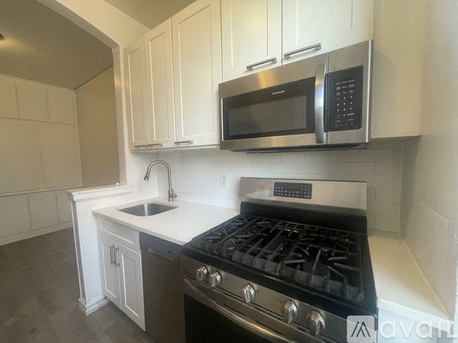 A kitchen with a stove, sink, and cabinets.