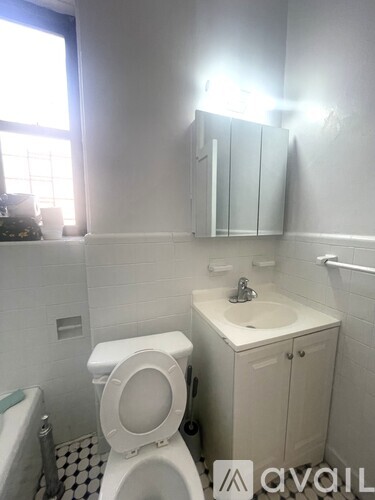 A white toilet sits in a bathroom with a sink and a bathtub.