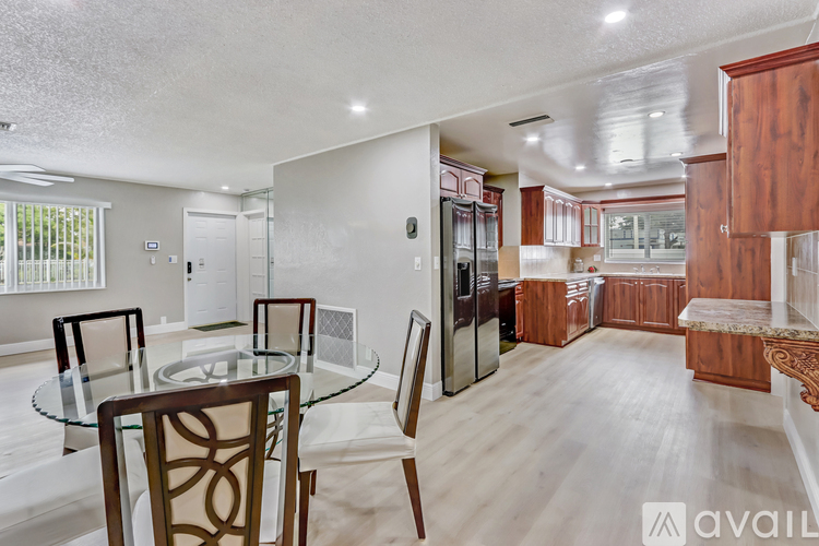 A modern kitchen with wooden cabinets and a glass table.