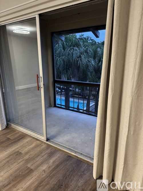 A balcony with a glass door leading to a pool area.