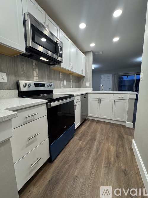A kitchen with white cabinets and a wooden floor.