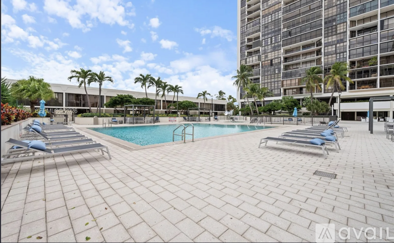 A pool area with sun loungers and a building in the background.