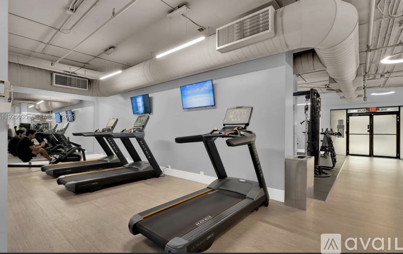 A gym with treadmills and a wall-mounted TV.