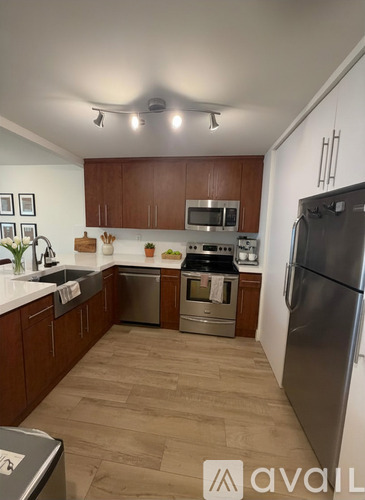 A kitchen with wooden cabinets and a stainless steel refrigerator.