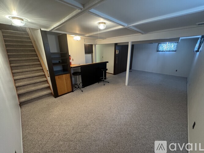 A spacious room with a staircase, a desk, and a chair.