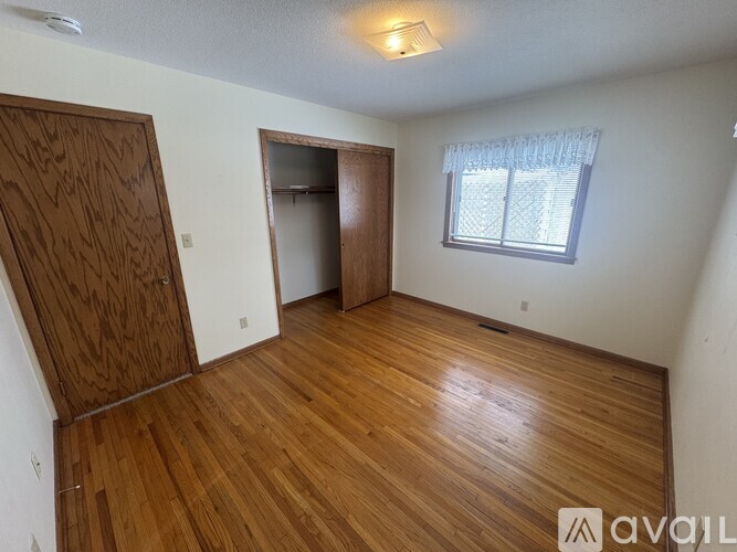 A room with wooden floors and a window with blinds.