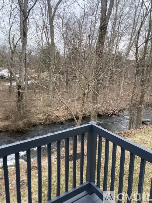 A balcony overlooks a river with trees in the background.