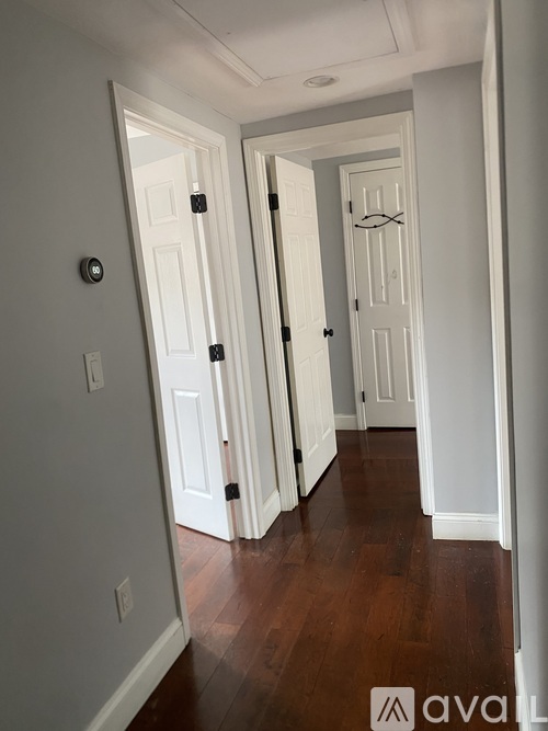 A hallway with white doors and wood floors.