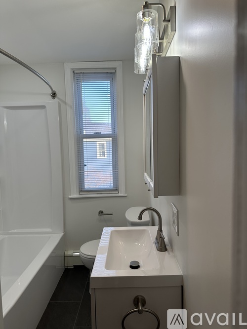 A bathroom with a white sink and a window with blinds.