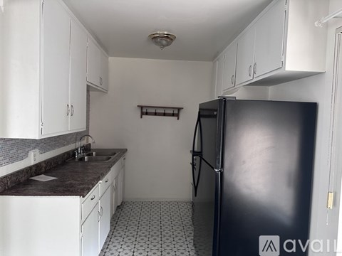 A kitchen with white cabinets and a black refrigerator.