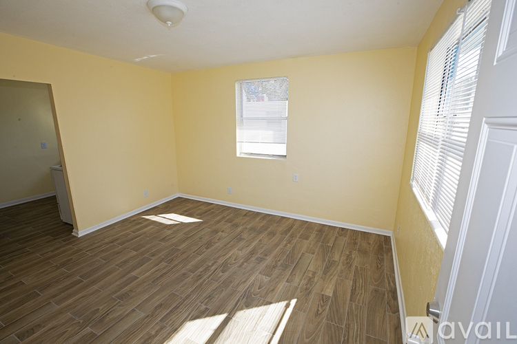A room with wooden flooring and a window with blinds.