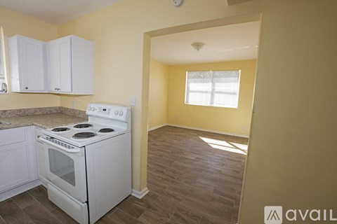A kitchen with a white stove and cabinets.