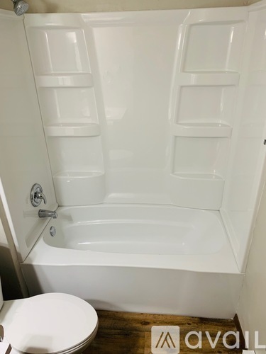 A white bathtub with a toilet in front of it.
