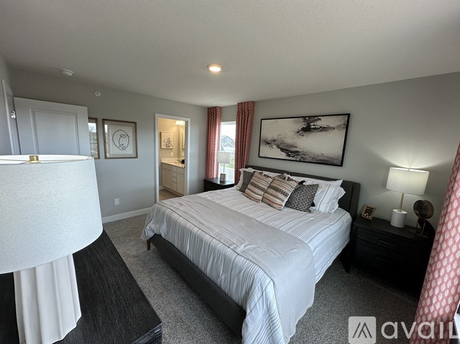 A bedroom with a large bed and a nightstand with a lamp.