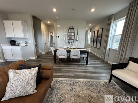 A living room with a brown couch and a dining table with chairs.