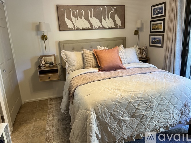 A bedroom with a large bed and a painting of birds on the wall.