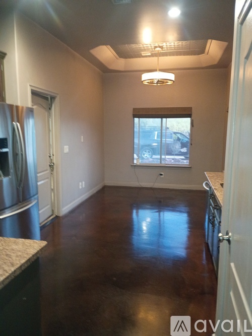 A kitchen with a refrigerator, cabinets, and a window.