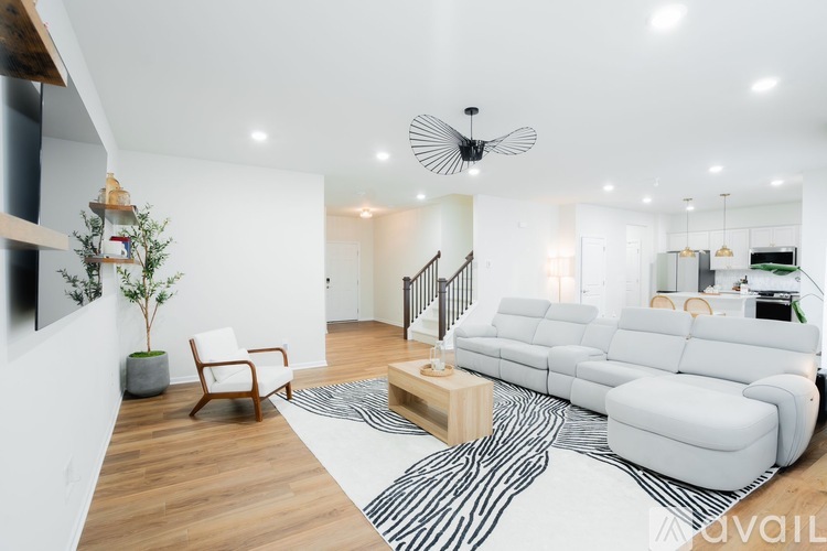 A living room with a white couch, a wooden coffee table, and a black and white rug.
