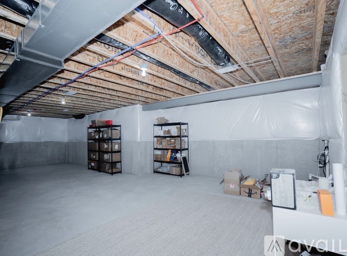 A sparsely furnished room with a concrete floor and exposed ceiling beams.