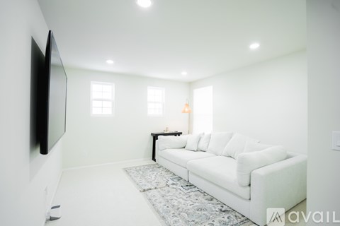 A living room with a white couch and a television on the wall.
