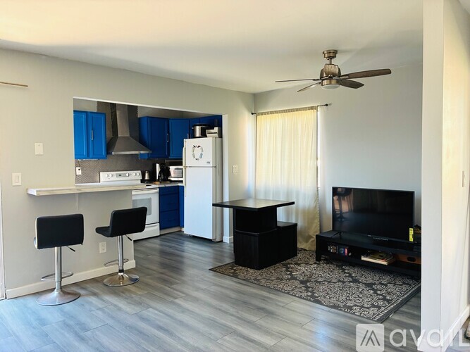 A living room with a television, a bar area, and a kitchen area.