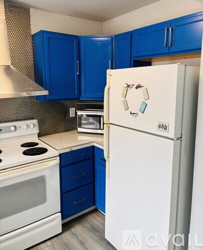 A kitchen with blue cabinets and a white fridge.