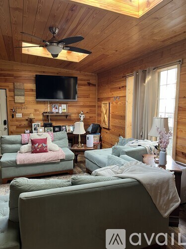 A living room with a couch, a bed, and a television on the wall.