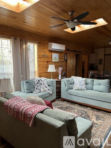 A living room with a couch, a rug, and a ceiling fan.