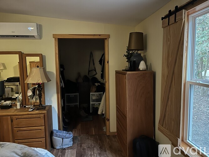 A bedroom with a wooden dresser and a mirror on the left side, and a wooden wardrobe on the right side.