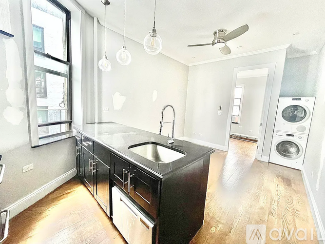A kitchen with a black counter top and wooden floors.