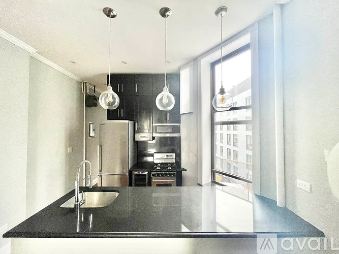 A modern kitchen with a black countertop and stainless steel appliances.