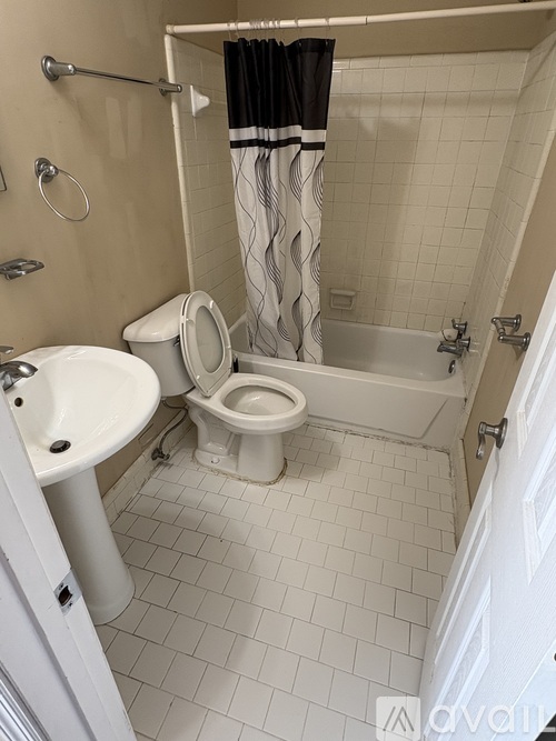 A white toilet is in a bathroom with a white sink and a bathtub.