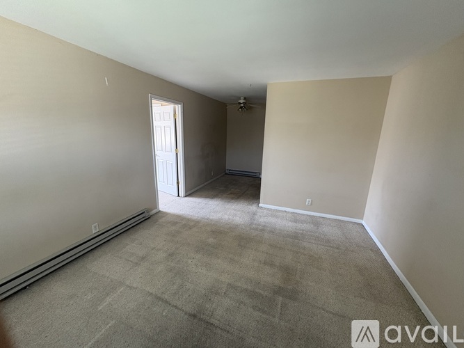 A room with a carpeted floor and a door leading to another room.