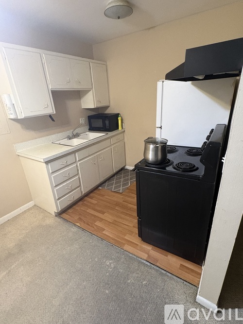 A small kitchen with a black stove and white cabinets.