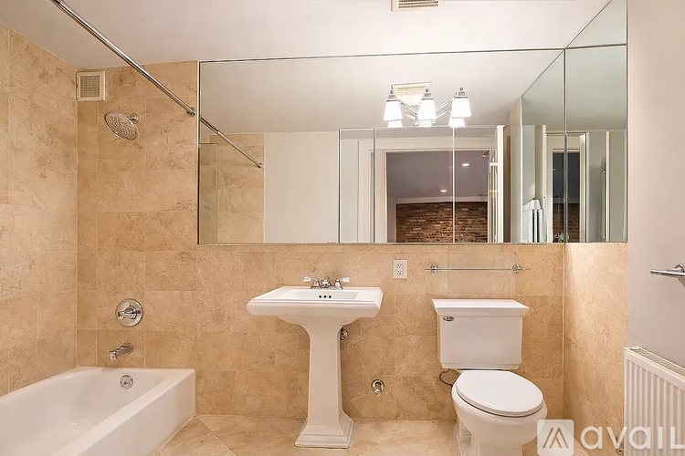A bathroom with a tub, sink, toilet and mirror.