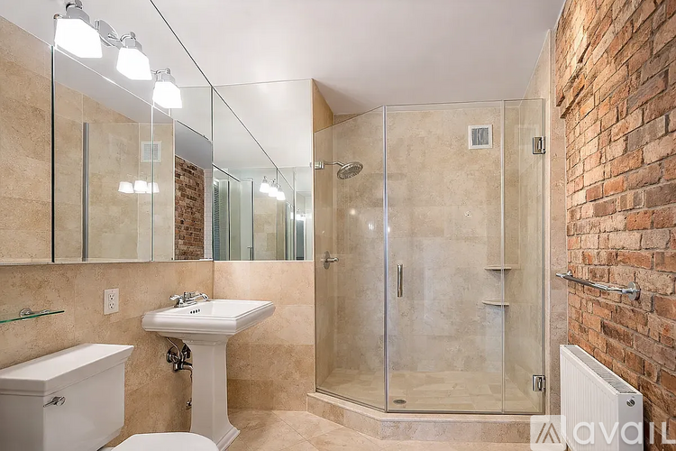 A bathroom with a white sink, toilet, and a glass shower stall.