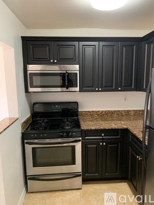A kitchen with black cabinets and a stove top oven.