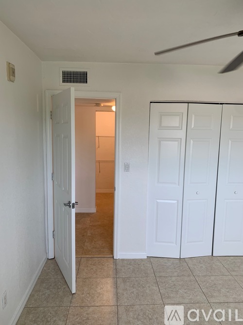 A room with a white door and a fan on the ceiling.