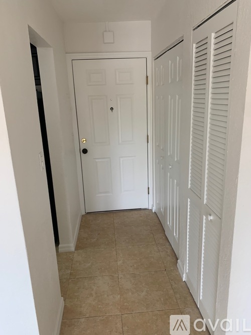 A white door is in a hallway with white walls.
