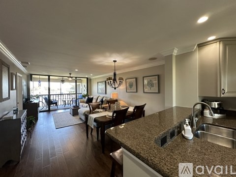 A well-lit kitchen and living room with a dining table and chairs.