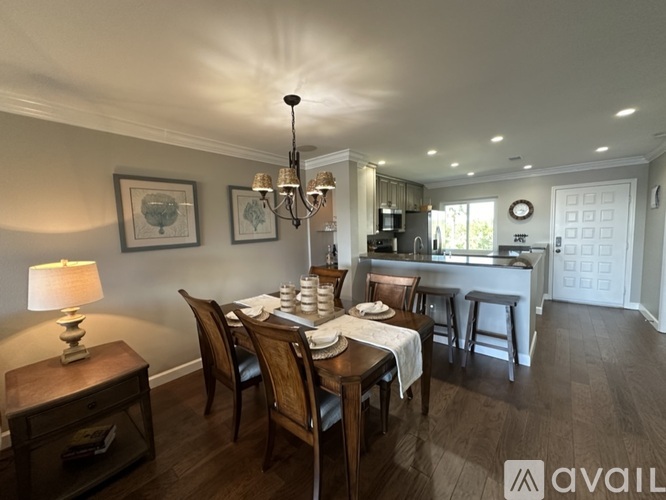 A well-lit dining room with a wooden table set for a meal.