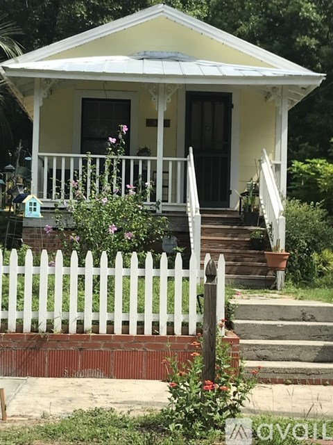 A small yellow house with a white picket fence.