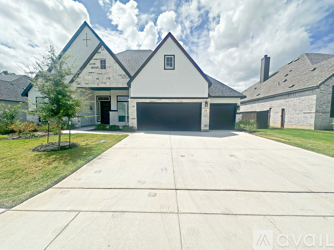 A white house with a black garage door and a driveway in front.