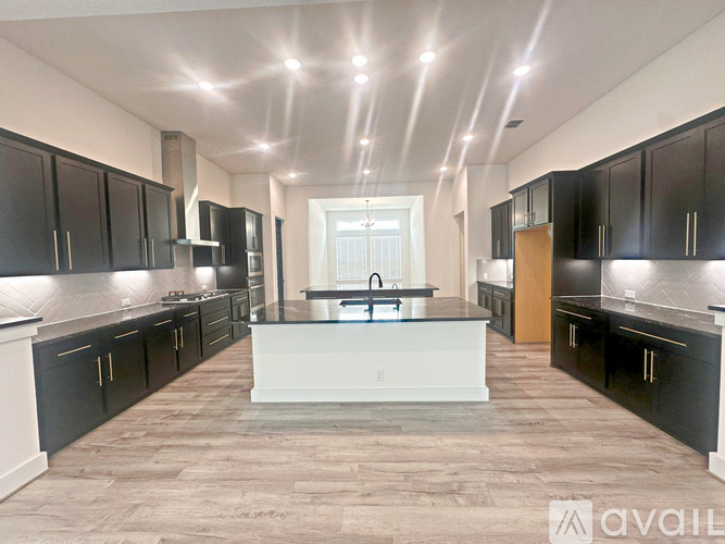 A spacious kitchen with black cabinets and a central island.
