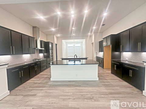 A spacious kitchen with black cabinets and a central island.