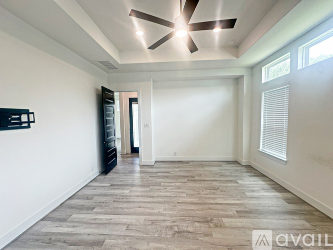A spacious room with a ceiling fan and wooden flooring.
